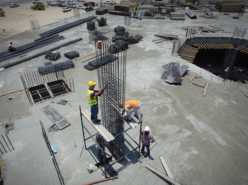 Aerial view of construction workers in safety gear working with rebar columns at an active building site